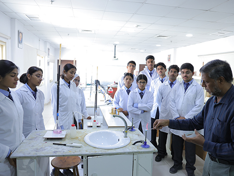 best secondary education Kuwait teacher with female students in uniform